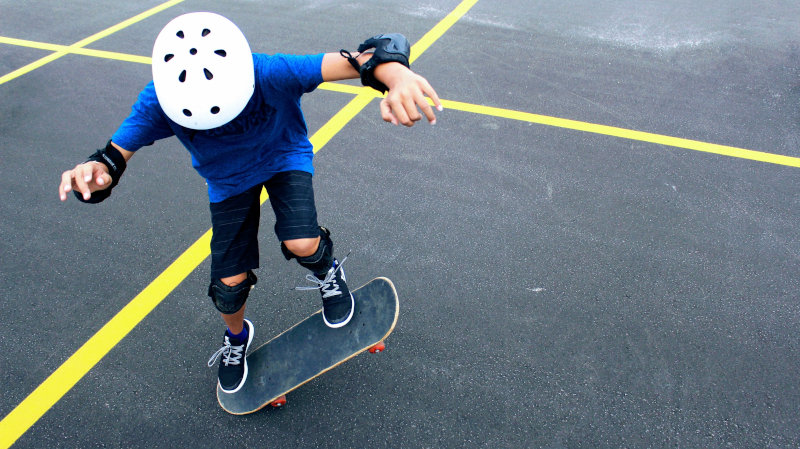 Kind mit Helm auf Skateboard