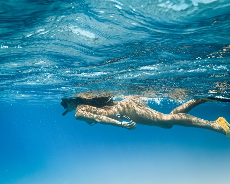 Frau schwimmt mit Schnorchelset und Flossen