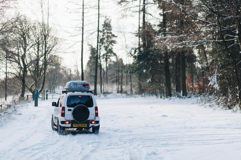 Auto mit Skibox im Schnee