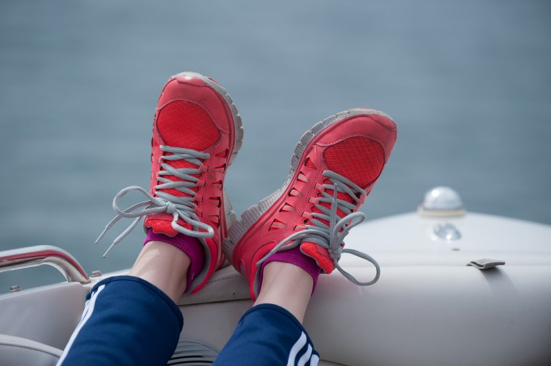 Eine Frau mit Segelschuhen legt ihre Füße entspannt auf der Schiffskante ab