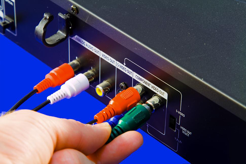 Vor blauem Hintergrund schließt eine Hand verschiedene Kabel an einen 5.1 Receiver an.
