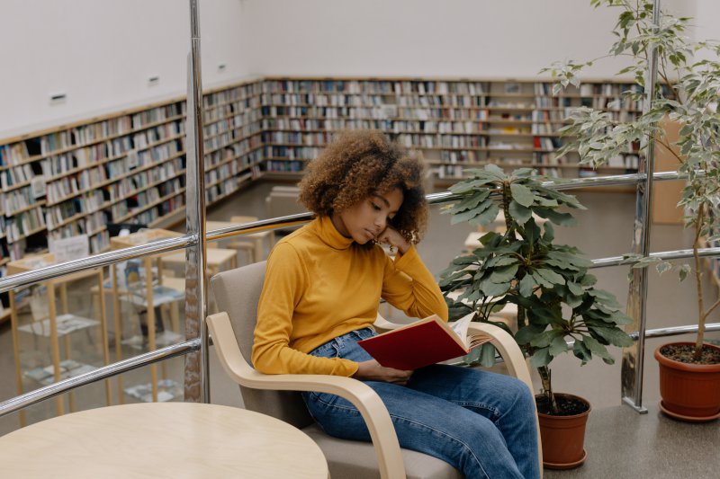 Mädchen liest ein Buch in einer Bibliothek